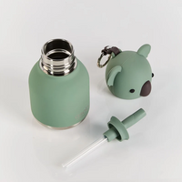 Introducing the Mini Koala Bestie Bottle Vacuum Flask from Asobu Bottle/AdnArt Inc—a green kids’ flask featuring a removable metal lid, straw, and a silicone cover shaped like an adorable koala head with ears and a convenient keychain. The playful animal design adds extra charm, while the vacuum insulation ensures drinks stay perfectly temperature-controlled. The items are displayed on a white surface.