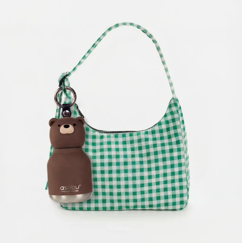 Sure! Here’s a rewritten sentence using the given product data: A green and white checkered handbag with a brown bear-shaped keychain and an Asobu Bottle Mini Brown Bear Bestie Bottle Vacuum Flask by AdnArt Inc attached to the strap, set against a plain white background.