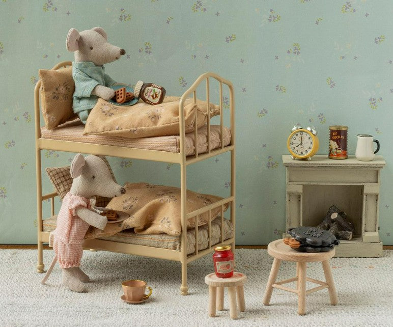 Two Maileg mice in pajamas enjoy a warm bedtime scene on bunk beds in a cozy, vintage-style room, complete with the Maileg Waffle set, Mouse by Maileg, as well as tea, snacks, books, a clock, a stove, and charming miniature furniture for imaginative pretend play.