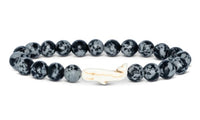 The Wayfare - Ocelli Stone Whale bracelet by fahlo features round, black and white speckled beads with a white whale-shaped charm—an ideal gift for marine life lovers.
