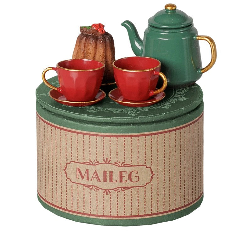 The Maileg Christmas tea party, Mouse - Red/Green set by Maileg features a green teapot, two red teacups with saucers, and a brown bundt cake arranged on a round, striped box—perfect for creating a festive holiday play set for your Maileg mice or hosting a charming Christmas tea party.