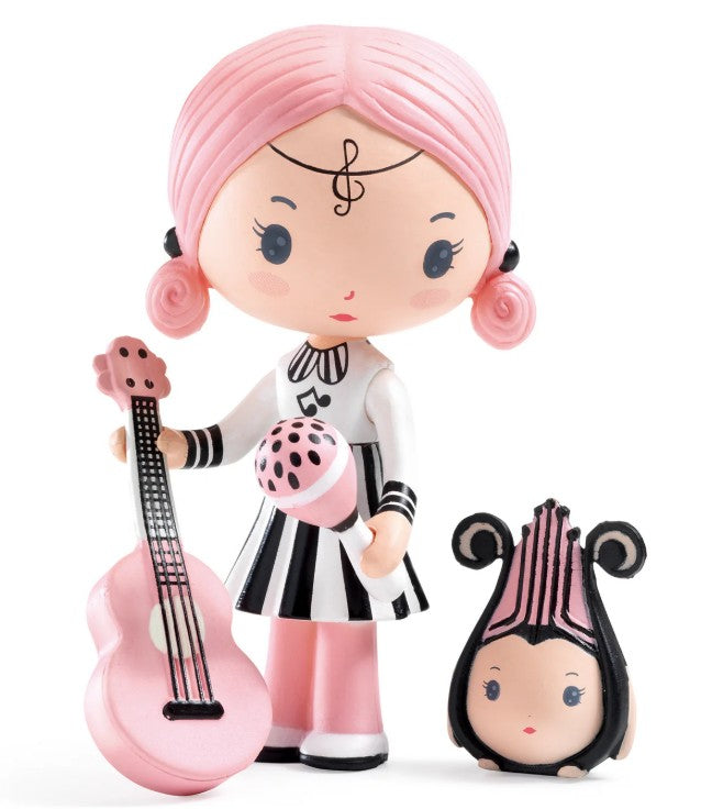 DJECO Tinyly Sidonie & Zick by DJECO features a figurine with pink hair holding a pink microphone, standing beside a pink guitar and a small matching animal companion. Sidonie is dressed in a black and white dress with musical notes on her forehead and microphone, making this miniature collectible the perfect gift for any music-loving fan.
