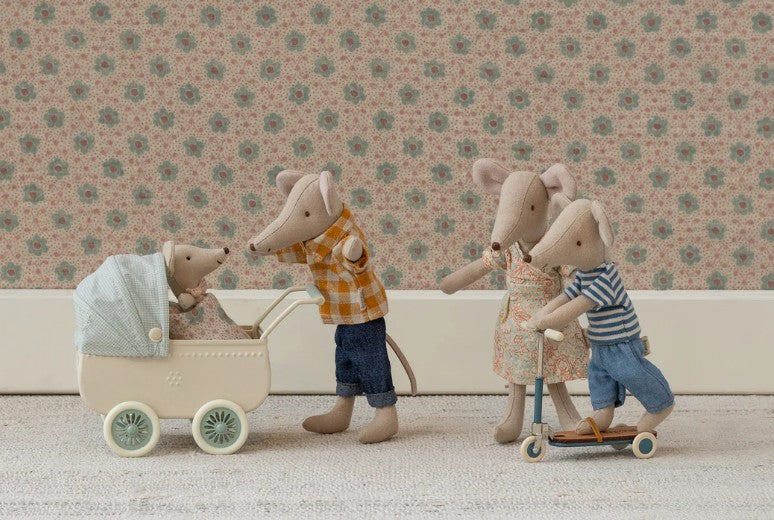 Maileg Mum Mouse by Maileg is dressed in a floral outfit and joins other family mice—a baby in a stroller, an adult in yellow plaid, and a child on a scooter—against vintage-style wallpaper for delightful family-themed play.
