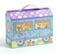 The DJECO Tinyly Bluchka & Indie House by DJECO is a colorful, illustrated box shaped like a caravan, adorned with flowers, pots, and a cat peeking out of a window. Featuring a purple handle on top, the box opens to reveal an enchanting miniature Tinyly house—a delightful playset perfect for housing Tinyly figurines.