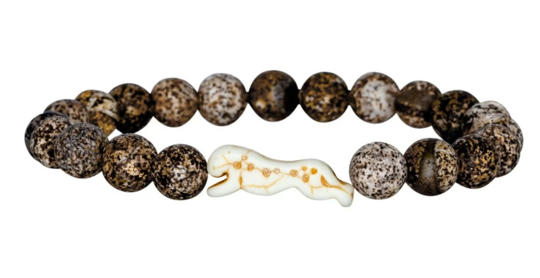 Sprint - Kalahari Cheetah by fahlo is a beaded bracelet with round, mottled brown and white stones and a carved cheetah-shaped bead, inspired by wildlife conservation and cheetah tracking.