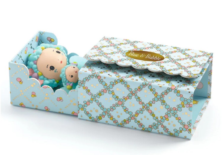 The DJECO Tinyly Blue Tinyroom by DJECO features a pastel blue patterned gift box, labeled "Blue & Bubble," which opens to reveal a charming doll and a small matching teddy bear—each with blue curly hair and reminiscent of the adorable Tinyly figures. The partially open box beautifully displays these delightful items inside.