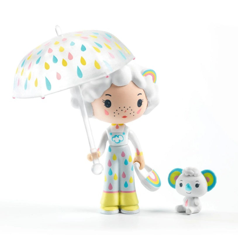 Add a touch of whimsy to your collection with the DJECO Tinyly Prunelle & Blanca set. This delightful figurine from DJECO features Prunelle, a charming doll with white hair holding a white umbrella adorned with colorful raindrops and dressed in vibrant, rainbow-themed clothes. She is accompanied by her adorable companion, Blanca—a petite gray koala with rainbow-colored ears—making this collectible duo an enchanting addition to any Tinyly assortment.