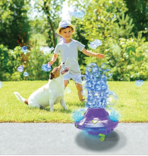 A young child and a dog enjoy a sunny day outdoors as colorful bubbles fill the air from the South Beach Bubbles PoppinColorz Galactic Color Bubble Machine.