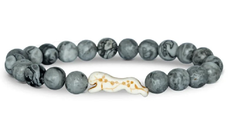 The Sprint - Cloudburst Cheetah bracelet by fahlo features round, gray marble-like beads and a white charm shaped like a running cheetah with brown spots—perfect for anyone passionate about protecting these magnificent animals.