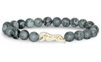 The Sprint - Cloudburst Cheetah bracelet by fahlo features round, gray marble-like beads and a white charm shaped like a running cheetah with brown spots—perfect for anyone passionate about protecting these magnificent animals.