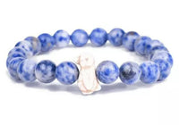 The Passage - Igloo Blue Penguin bracelet by fahlo features round blue marbled beads and a single white rabbit-shaped bead, displayed on a white background—great for wildlife conservation fans or as a unique penguin-themed accessory.