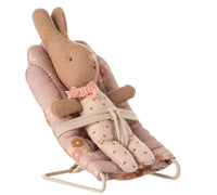 A stuffed bunny in a pink polka-dot outfit sits in the Maileg Babysitter, My - Rose by Maileg—a floral-patterned seat perfectly sized for my-sized Maileg mice and featuring a safety strap.