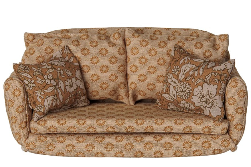 A charming Maileg Sofa Bed, Mouse, Large – Ocher, from Maileg, features a cozy ocher tone with a repeating floral pattern and includes two matching floral pillows—evoking the iconic Maileg mouse sofa bed style and beautifully displayed against a white background.