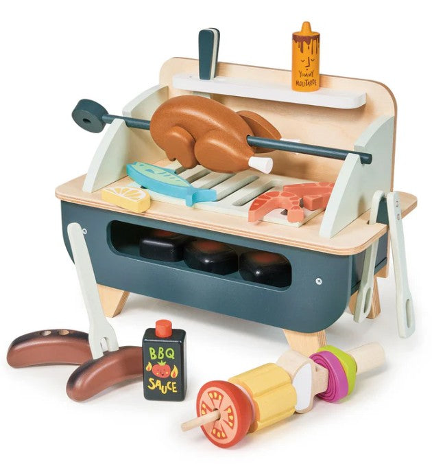 The Tenderleaf Barbeque Play Set is a wooden tabletop grill that comes with play food accessories like chicken on a rotisserie, sausages, veggies, a kebab, BBQ sauce bottle, and tongs for realistic pretend play.
