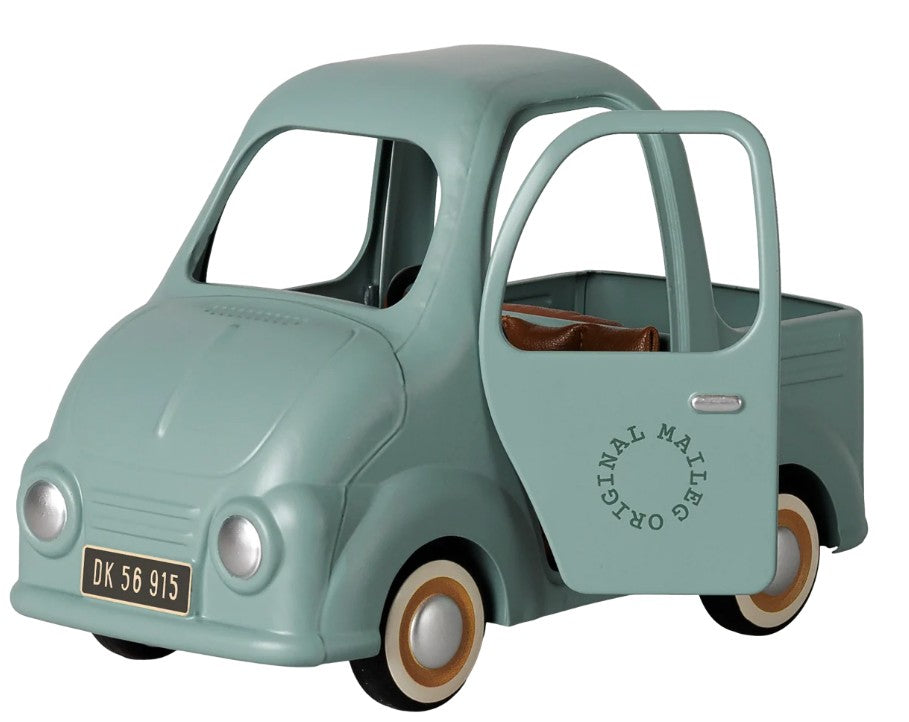 A small, mint green Maileg Truck, Mouse with an open door, brown seats, and white-rimmed wheels. Perfectly sized for mice, this miniature truck by Maileg features “Original Maileg” on the side and a DK 56 915 license plate.