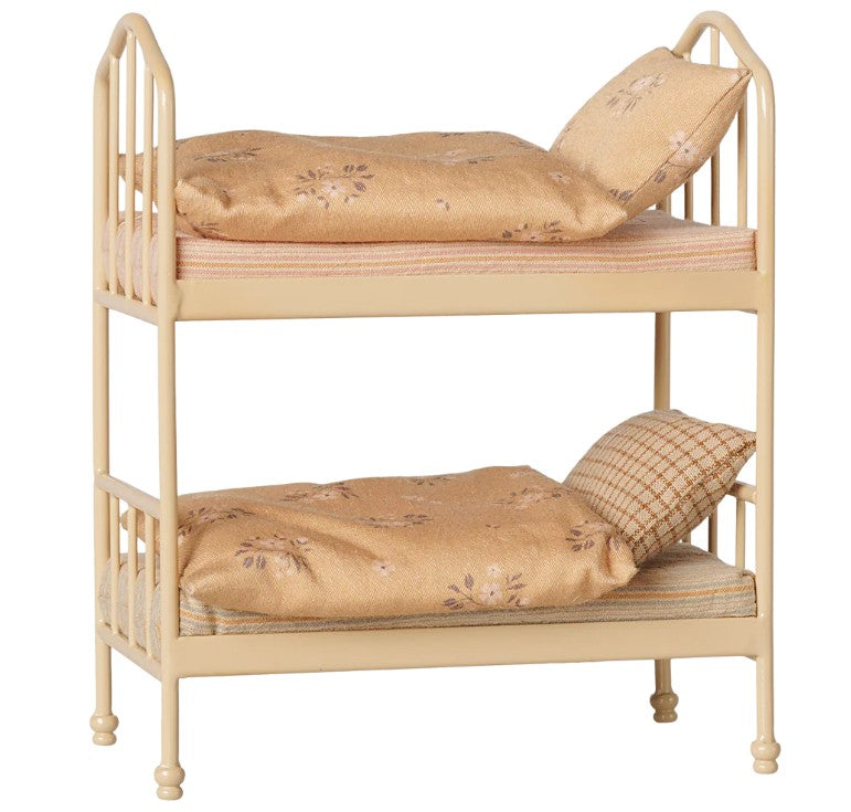 The Maileg Bunk bed, Mouse - Wheat by Maileg is a small beige metal bunk bed featuring ornate rails and delicate four rounded legs. Each level comes complete with a mattress, pillow, blanket, and beautiful gold and floral bedding—perfect for outfitting your mouse house in style.