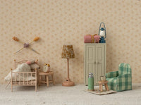A miniature vintage-style bedroom scene featuring a small bed, nightstand, alarm clock, lamp, green plaid armchair, cabinet, thermos, cups, and the Maileg Vintage Lantern for Mouse in Blue by Maileg against beige floral wallpaper.