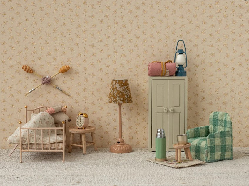 A miniature vintage-style bedroom scene featuring a small bed, nightstand, alarm clock, lamp, green plaid armchair, cabinet, thermos, cups, and the Maileg Vintage Lantern for Mouse in Blue by Maileg against beige floral wallpaper.