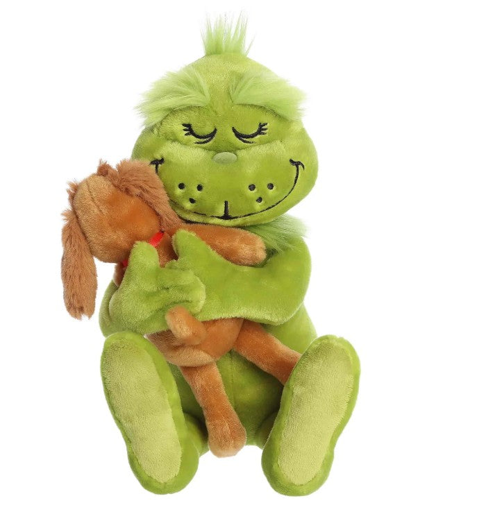 A fuzzy, green Holiday Hugs plush by Aurora features a smiling Grinch with closed eyes hugging a brown plush dog. Both are seated together, and the Grinch’s tuft of green hair adds to their festive charm—making this adorable duo a perfect holiday gift for fans of cuddly toys.