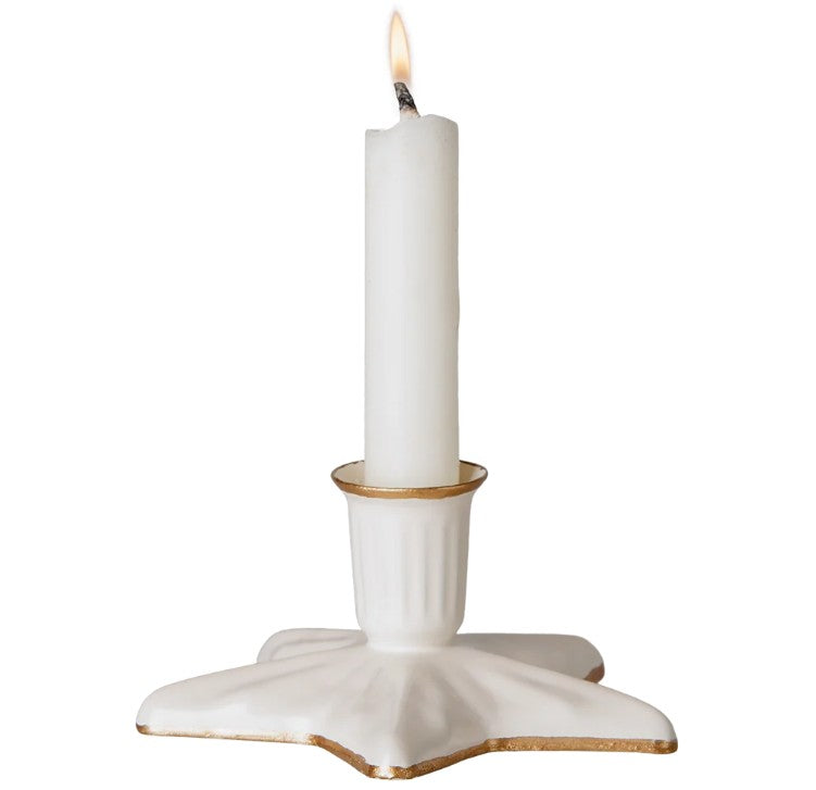 A lit white candle rests elegantly in the Maileg Candle holder, Star, Small by Maileg—a small decorative holder featuring gold trim, beautifully showcased against a plain background.