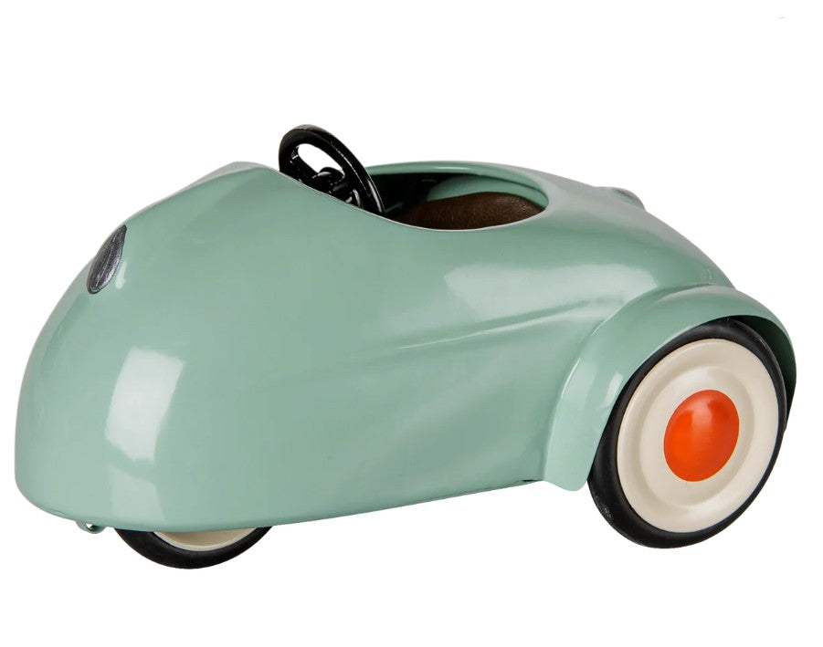 A small, vintage-style Maileg Car, Mouse in light mint by Maileg, featuring a minimalist design with white wheels accented by orange centers, a black steering wheel, and an open circular seat—perfect for mice toys in search of a charming miniature car journey.