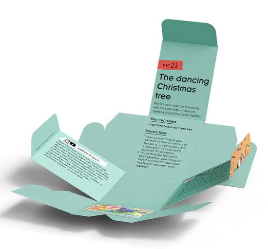A light green, partially open cardboard box from Thames & Kosmos displays printed instructions and vibrant graphics. The text highlights "Day 23: The Dancing Christmas Tree" and details the required materials and steps for an interactive experiment, all as part of The Thames & Kosmos Science Advent Calendar packed with engaging STEM activities.