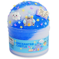 The Enchanted Castle Slime by Peachybbies Slime comes in a small jar and features blue fantasy slime with sparkling glitter, star confetti, and whimsical decorations including a cloud, a castle, and a magical book—ideal for sensory play. The packaging showcases delightful illustrations of a castle and book.
