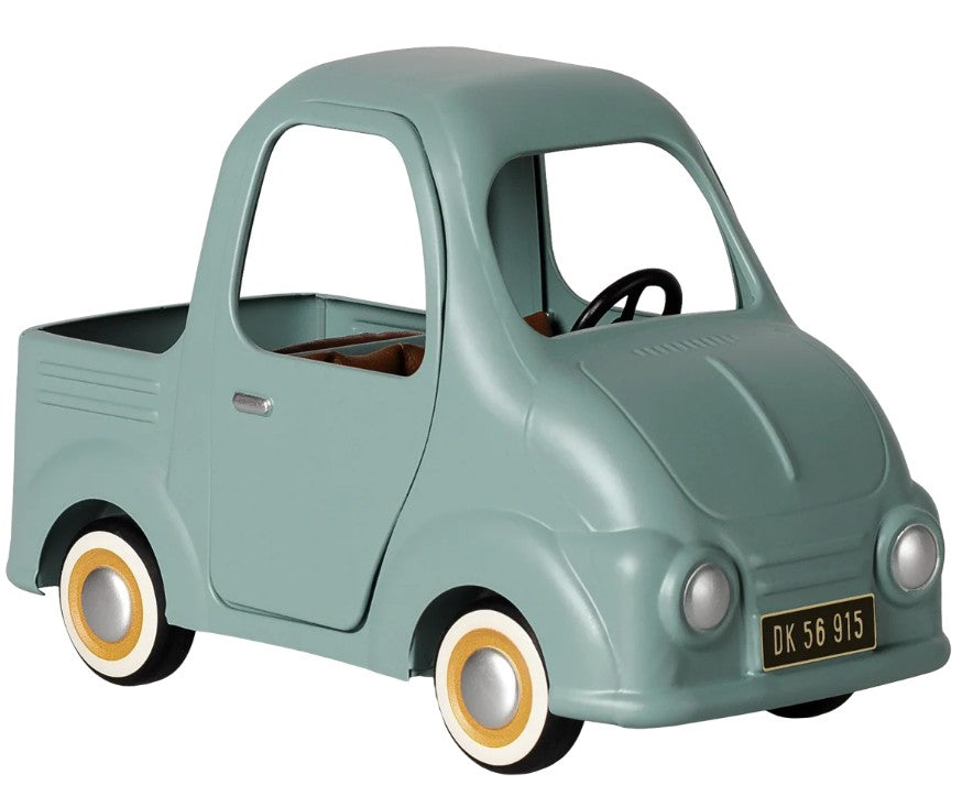 The Maileg Truck, Mouse by Maileg is a light blue vintage-style miniature pickup truck featuring a small bed, round headlights, whitewall tires, and a black license plate marked DK 56 915. Designed to be mouse-sized, this charming vehicle has no windows or visible seats.