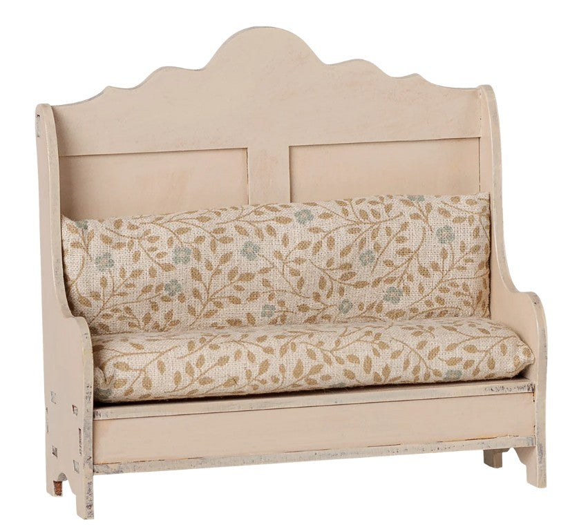 The Maileg Kitchen Bench, Mouse - Light Sand from Maileg is a charming small wooden bench featuring a scalloped back, light sand-colored paint, and a patterned cushion adorned with delicate brown leaves and soft green touches—perfectly sized for Maileg mice to dine in style.
