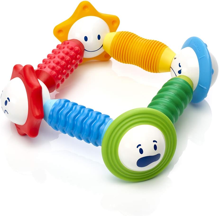 The Smart Toys Smartmax My First Sounds & Senses is a colorful baby teething toy with four textured handles in red, yellow, blue, and green that support motor skills and sensory play. Each handle connects to a white face with happy, surprised, content, and sad expressions.