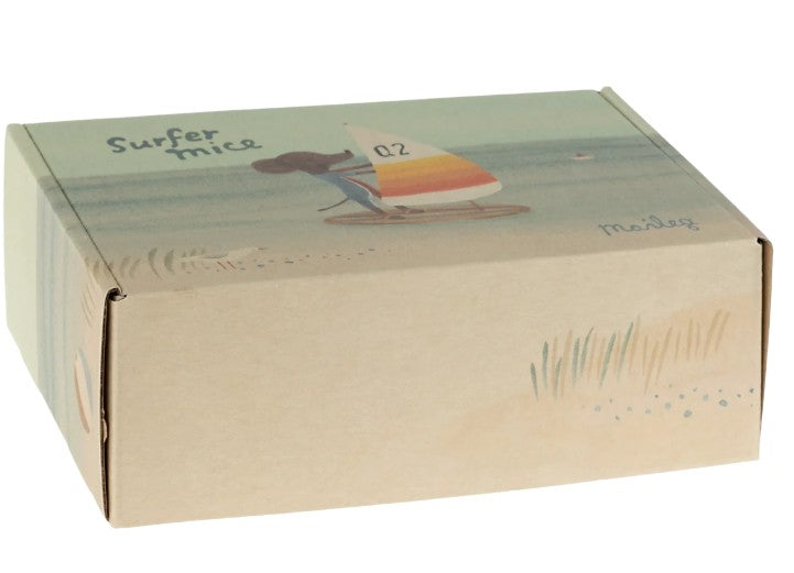 A cardboard box featuring an illustration of a Maileg Beach mice, Surfer big brother windsurfing on the water, with the Maileg brand name in the corner. Light beach grass adorns the foreground of this charming packaging, making it perfect for fans of the Surfer big brother beach toy.