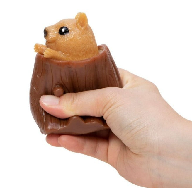 A hand squeezes the Nutty Squirrel Popper by Schylling Toys, a brown stress relief fidget toy shaped like a tree stump with an adorable squirrel popping out of the top—making it a delightful sensory toy for unwinding moments.