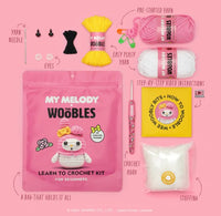 The Woobles My Melody Crochet Kit for beginners includes a project bag with a crocheted My Melody image, yarn needle, eyes, yarn, easy-peasy yarn, instructions, crochet hook, and stuffing.