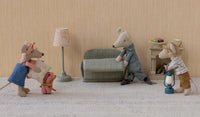 Three Maileg Mouse toys in a dollhouse living room: one in a blue dress with gifts, another in pajamas by a blue sofa, and a third in overalls beside the Maileg Vintage Floor Lamp, Mouse - Mint and a small table with cake.