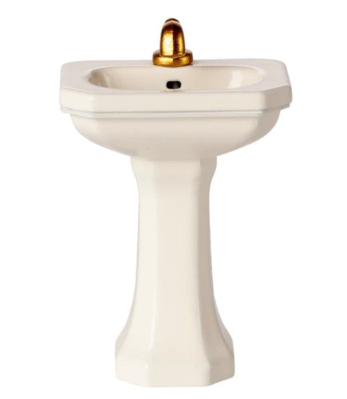 The Maileg Bathroom Sink, Mouse - Off white by Maileg is a compact white pedestal sink with a gold faucet, ideal as a miniature bathroom fixture for Maileg mice or any Maileg mouse collection, shown isolated on a white background.