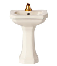 The Maileg Bathroom Sink, Mouse - Off white by Maileg is a compact white pedestal sink with a gold faucet, ideal as a miniature bathroom fixture for Maileg mice or any Maileg mouse collection, shown isolated on a white background.