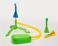 The D&L Stomprocket Dino-Soar Stomp Rocket Kit features a toy rocket launcher with a green base, a yellow tube, and three vibrant dinosaur-themed rockets—one positioned on the launcher and two on the ground—making it perfect for inspiring STEM learning through imaginative play.