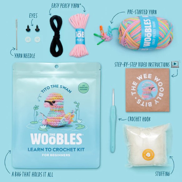 The Woobles Tito the Swan Pastel Crochet Kit for beginners includes a resealable bag with a swan image, colorful yarn, crochet hook, stuffing, plastic eyes, yarn needle, pre-started yarn, video instructions, and a small box.