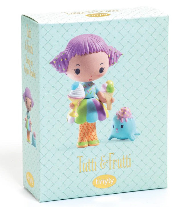 The DJECO Tinyly Tutti & Frutti toy box by DJECO features an adorable miniature collectible doll with purple hair holding ice cream, dressed in a colorful outfit, and standing beside a small blue creature. The packaging displays the names "Tutti & Frutti" and "Tinyly" on a light patterned background, highlighting this charming Tinyly collectible figure.