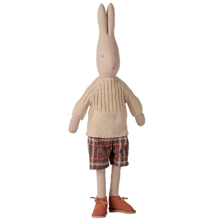 A stuffed rabbit toy dressed in Maileg Pants and knitted sweater, Size 4 - Off white, styled with charming orange shoes and plaid shorts, standing upright on a white background.