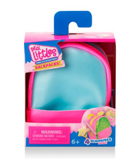 The Toysmith Moose Toys - Real Littles Charms Backpacks come in blue and pink packaging with a warning label and "4 surprises inside" text, featuring fun miniature surprises—perfect for fans of charms backpacks and suitable for ages 6 and up.