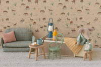 The Maileg Little Brother Mouse In Matchbox by Maileg rests on his matchbox bed in a miniature room with Western-themed wallpaper, pastel furnishings, a sofa, table with tea and cake, chairs, a clock, and a lantern.