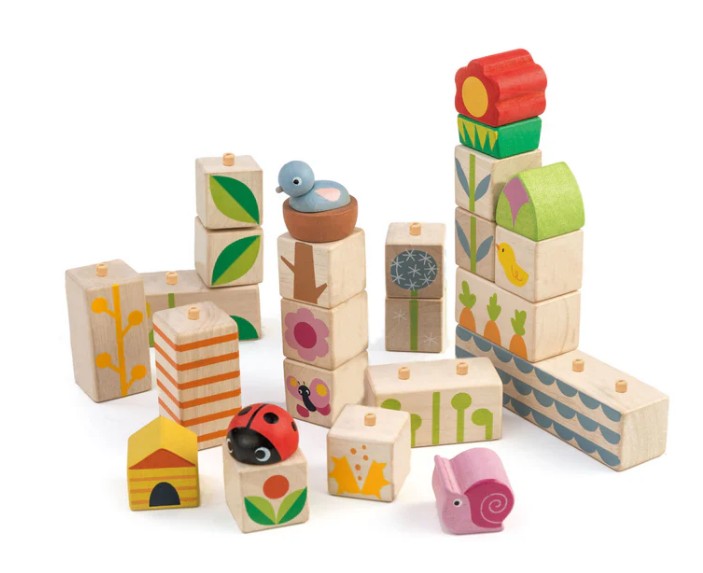 Tenderleaf Garden Blocks, featuring colorful nature-themed designs like flowers, leaves, a bird, ladybug, snail, and beehive, inspire imaginative play as children stack and create playful wooden structures.