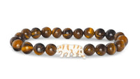 Introducing the fahlo Prowl - Tiger's Eye bracelet, featuring round brown Tiger's Eye beads and a central white elephant-shaped bead, thoughtfully crafted to support wildlife conservation.