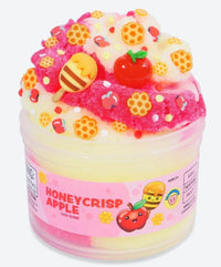 A jar of Peachybbies Slime's Honey Crisp Apple Slime offers a delightful sensory experience with its pink and yellow swirls, topped with faux apple, honeycomb, and honey details. The label features cartoon apples and honeycombs, capturing the autumn-inspired charm of this Honey Crisp Apple Slime.