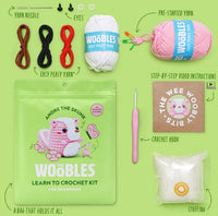 The Woobles Andre the Skunk Pink Crochet Kit includes colored yarn, plastic eyes, a pre-started piece, crochet hook, stuffing, yarn needle, video instructions, and a storage bag for your finished skunk—perfect for beginners.