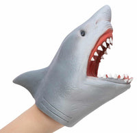 A hand is wearing a gray Schylling Toys Shark Hand Puppet, which features an open mouth displaying sharp teeth and a bright red interior. Ideal for pretend play or puppet shows, this cartoon-like shark puppet brings imaginative stories to life.