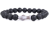 The fahlo Voyage - Lava Stone Shark bracelet showcases round black lava stones with a central white shark-shaped bead—ideal for ocean conservation enthusiasts.