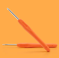 Two orange-handled crochet hooks with metal tips—one embossed with JASPER, the other with WOOBLES—are shown against an orange background. They’re from The Woobles Jasper the Zebra Crochet Kit, perfect for beginners or adding to your crochet supplies.
