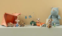 A Maileg Mouse camp scene features the Maileg Fishing Set, Mouse, with a tent, clothesline, canoe, fishing gear, net, and a large blue rhino plush against a beige background.